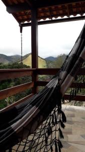 a hammock on a porch with a view at Pousada Recanto da Serra in São Pedro da Serra