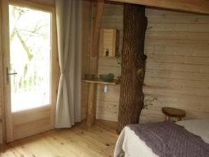 Un dormitorio con un árbol, una cama y una ventana en Domaine de la Boere, en Beaulieu-sous-la-Roche
