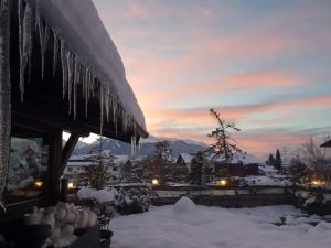 a house covered in icicles in the snow at sunset at Alp Art Hotel Götzens in Innsbruck