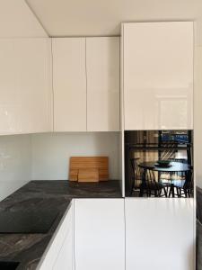 uma cozinha com armários brancos e uma mesa em Apartment KORA em Pervalka