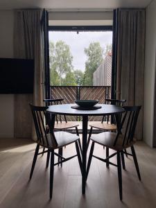 a dining table and chairs in a room with a window at Apartment KORA in Pervalka