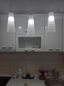a kitchen with white cabinets and a sink and lights at Đurđevak lux in Banja Koviljača