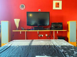a bedroom with a tv and a table with a bed at Modern Red & Blue Apartment in Podstrana