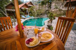a table with a plate of food next to a pool at The Lanjang valley Bungalow in Nusa Penida