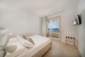 a bedroom with a bed with a view of the ocean at Jatika Boutique Hotel in Aglientu