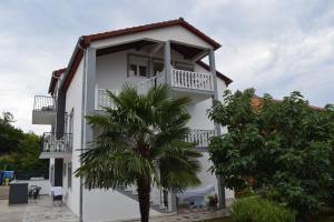 ein weißes Gebäude mit einer Palme davor in der Unterkunft Apartments Malinska-Kajkić in Malinska