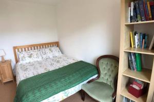 a bedroom with a bed with a chair and a book shelf at Nyth Y Wiwer, Spacious and Peaceful Bungalow Near Harlech in Llanfair