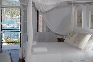 Schlafzimmer mit einem weißen Bett und einem Balkon in der Unterkunft Neoclassical manor house in Poros