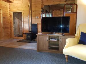 a living room with a flat screen tv on a entertainment center at Cabin at Aithernie in Leven