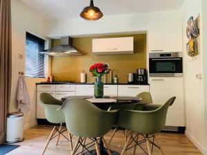 uma cozinha com uma mesa com cadeiras e um vaso de flores em Zonnebos, private garden, fresh air, relax! em Otterlo