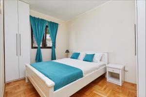 een witte slaapkamer met blauwe gordijnen en een bed bij Kotor Sunset Apartments in Kotor +40 foto's