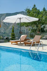 een zwembad met 2 ligstoelen en een parasol bij Kotor Sunset Apartments in Kotor
