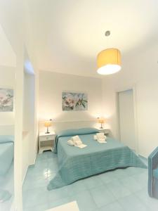 ディアマンテにあるVilla Pietra Rossaの白いベッドルーム(青いベッド1台、ランプ2つ付)