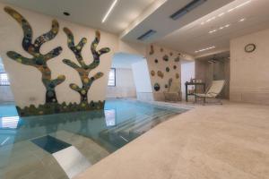 hol z basenem z drzewami na ścianie w obiekcie Dolomiti Hotel Cozzio w Madonna di Campiglio