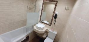 a white bathroom with a sink and a mirror at Hôtel des Pyrénées - Entre Bastille et Nation in Paris