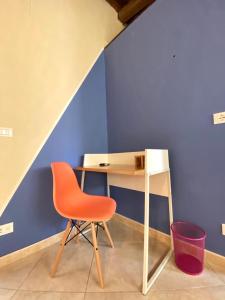 uma secretária com uma cadeira laranja ao lado de uma parede azul em Al Teatro em Reggio di Calabria