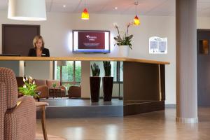 a woman standing at a reception desk in a waiting room at Escale Oceania Nantes in Bouguenais
