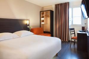 Una habitación de hotel con una gran cama blanca y un escritorio. en Escale Oceania Nantes Aéroport, en Bouguenais