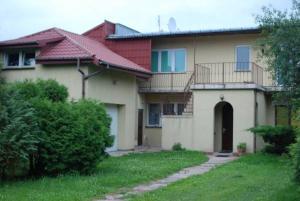 ein Haus mit einem Rasenplatz und einem Haus in der Unterkunft MHostel in Piaseczno