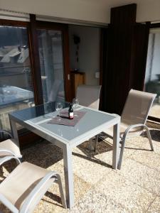 a glass table with two wine glasses and two chairs at Kuckuckstraum in Schönwald