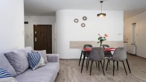 a living room with a couch and a table with chairs at Lesna Dreams Apartament in Pobierowo
