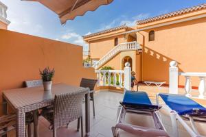 una casa y un patio con mesa y sillas en Los Cristianos Royal Gardens en Playa de las Américas