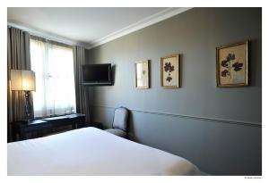Hotel De La Treille في ليل: غرفة نوم بسرير وتلفزيون على جدار