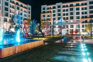 a fountain in front of a building at night at Luxury Studio Mamaia Nord in Mamaia Sat/Năvodari