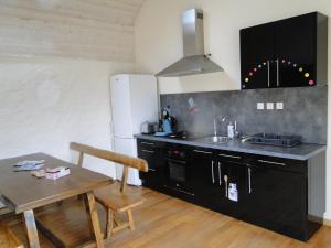 a kitchen with black cabinets and a sink and a table at Ty Clara in Landéda