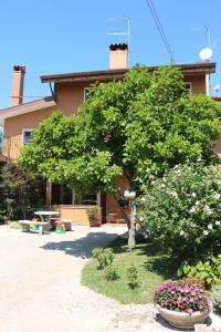 a tree in front of a building with flowers at Casa Flora in Treppo Grande