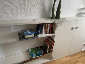 Un estante blanco con libros y un jarrón. en MeinJork, en Jork