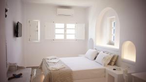a white bedroom with a bed and a window at Paraporti in Chora Folegandros