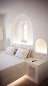 a white bedroom with a bed and a table at Paraporti in Chora Folegandros