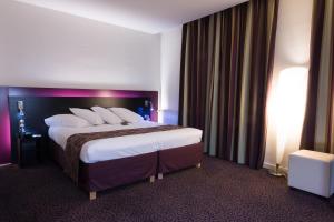 ein Hotelzimmer mit einem großen Bett mit weißen Kissen in der Unterkunft Mercure Lille Roubaix Grand Hôtel in Roubaix