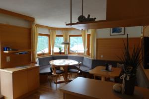 een keuken met een tafel, stoelen en ramen bij Apart La Stella in Kappl