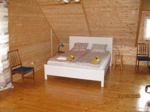 a bedroom with a white bed in a room with wooden walls at Drewniany domek w Otominie in Otomin