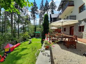a backyard with a table and chairs and an umbrella at Vila Felix in Sinaia
