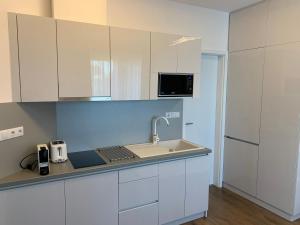 een keuken met witte kasten en een wastafel bij Naplemente Apartman in Balatonfüred