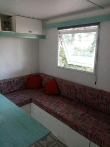een woonkamer met een bank en een raam bij mobil home du houx in Châtignac
