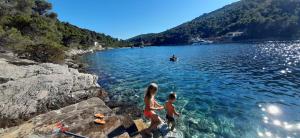 two people standing on rocks in a body of water at Apartment Nono Ivo in Vis