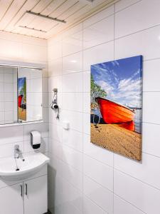 a bathroom with a red boat painting on the wall at Hotelli Kuohu Kangasala - Hotel and Apartments by UHANDA in Kangasala