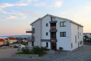 a white building with balconies on a street at Pansion Leggero in Krk