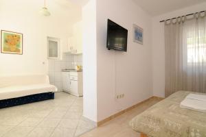 ein weißes Zimmer mit einem Bett und einem Fernseher an der Wand in der Unterkunft Villa Zvonko in Makarska