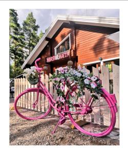 Una bicicleta rosa estacionada frente a un edificio con flores en Hotelli Hirsiranta, en Ruokolahti
