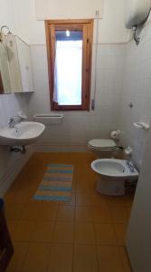 a bathroom with a sink and a toilet and a window at Sa Prama Pineta in Orosei