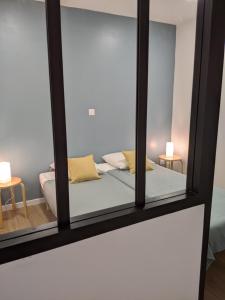 einem Spiegel, der ein Bett in einem Zimmer reflektiert in der Unterkunft Appartement 10A - RDC-centre ville-local vélo in Malestroit