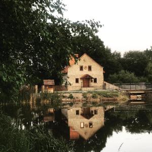 stary dom siedzący obok wody w obiekcie Wiśniowy Młyn w mieście Wiśniowa