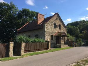 una vieja casa de piedra con una valla al lado de una carretera en Wiśniowy Młyn en Wiśniowa