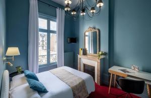 1 dormitorio con paredes azules y 1 cama con espejo en Hôtel de Paris en Limoges