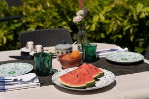 un tavolo con un piatto di anguria e un cesto di frutta di Muggia Uphill B&B a Múggia